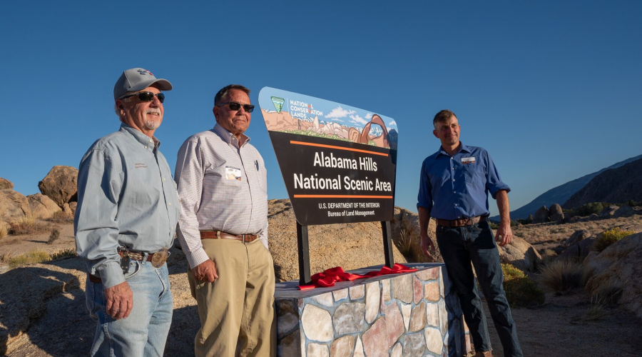 Supervisors Pucci and Kingsley to the left and Supervisor Griffiths to the right of a large sign announcing the new Alabama Hills National Scenic Area