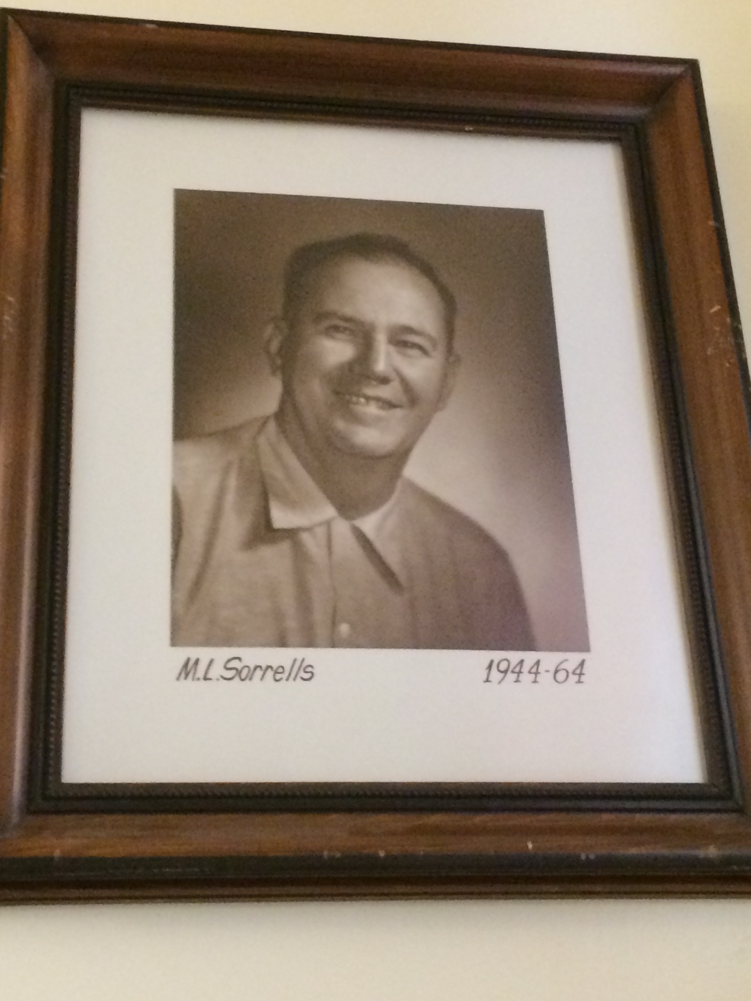 Photo of sepia-toned framed photo of a man hanging on white wall.