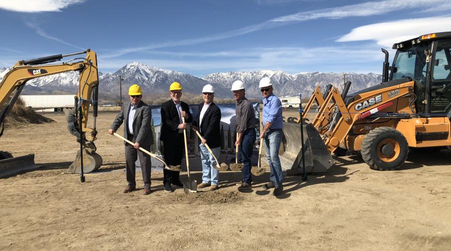 Five guys wearing hard hats and holding shovels with dirt on them