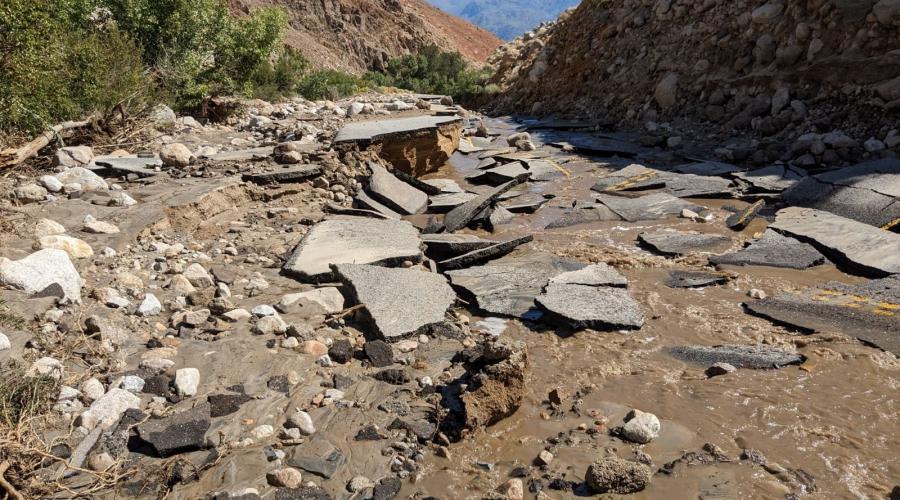 Road covered in dirt and rock, with asphalt destroyed and in chunks.