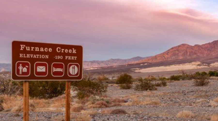 Sign in desert that states "Furnace Creek" and has symbols for amenities