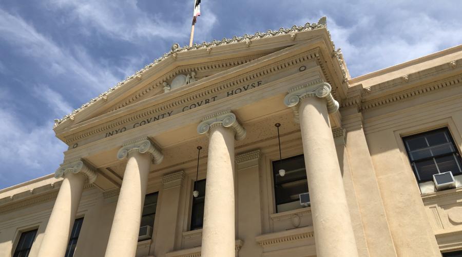 Beige courthouse building with columns and blue sky in background