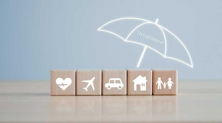 Umbrella over wooden blocks depicting different types of insurance.