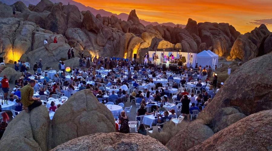 Unusual rock formations surround dozens of formal dining tables as the sun sets.