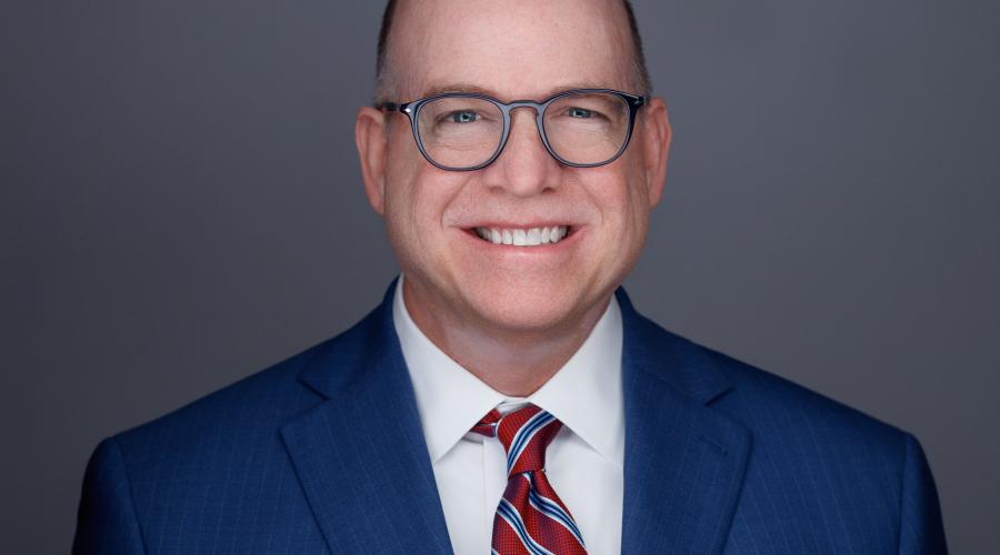 bald smiling man with glasses in navy blue suit