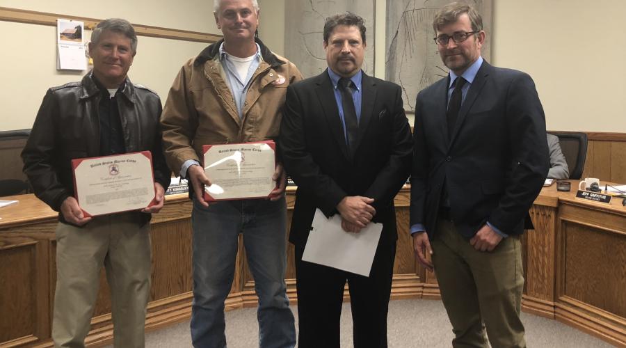 Four men standing in front of the Board of Supervisors wooden dais