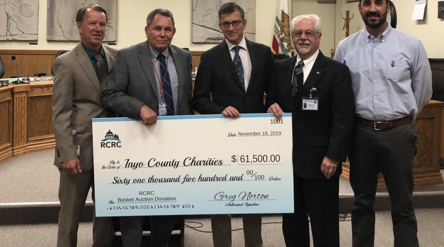 Five men standing in front of wooden dais in Board of Supervisors chambers with four of them holding a giant novelty check