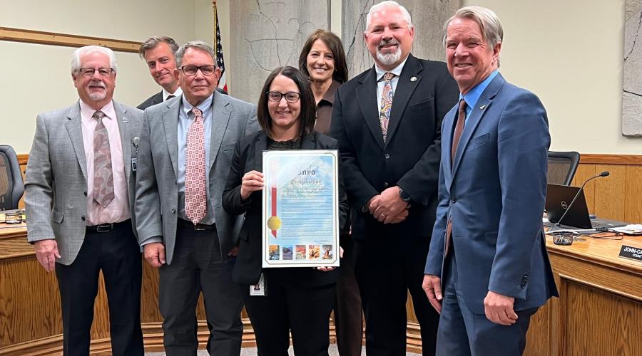 Seven people standing next to each other while one holds a framed document.