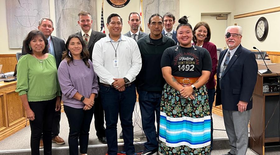 Members of the Board of Supervisors standing in front of the podium with members of the Bishop Tribal Council.