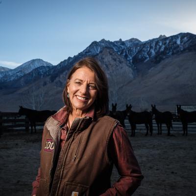 Woman Standing in Front of Mountain Range Around Dusk